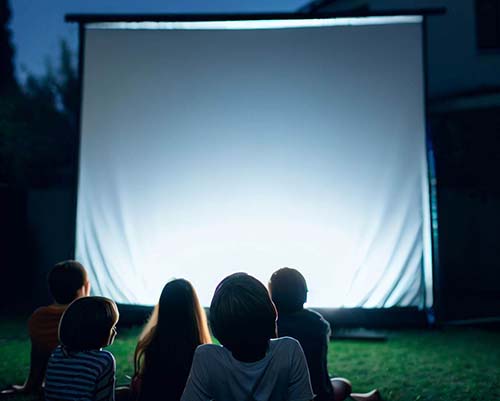 kids watching movie projector outdoors